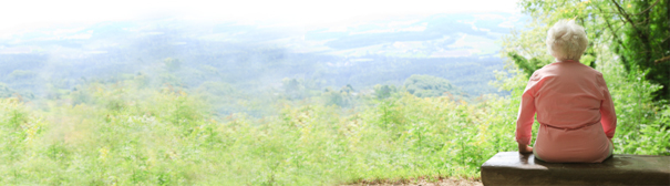 A woman sitting on a mountain top bench.