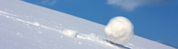 A giant snowball rolling down a snow covered hill.
