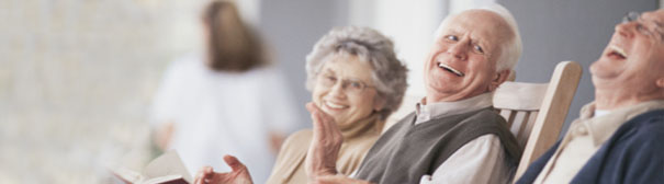 Three older people laughing in rocking chairs.