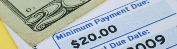 A bill with a minimum payment of $20.00, and the corner of a $20 bill.