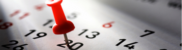 A red thumbtack stuck into the number 20 on a calendar.